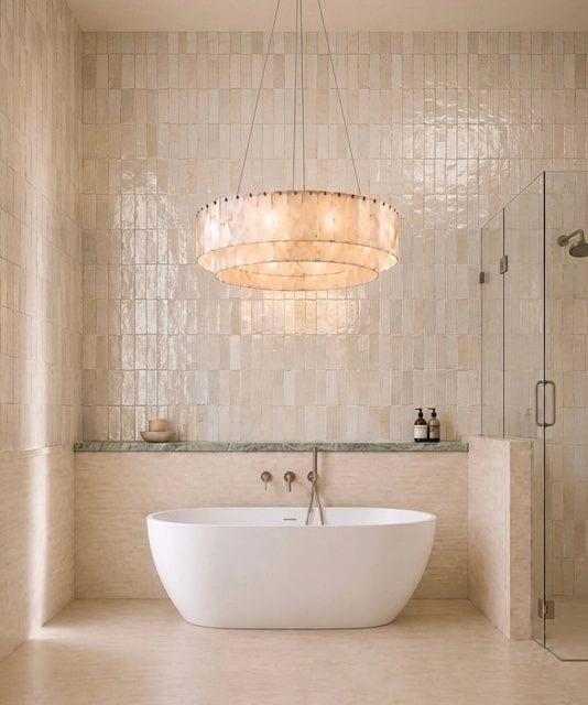 Freestanding tub under a designer pendant with terrazzo detail