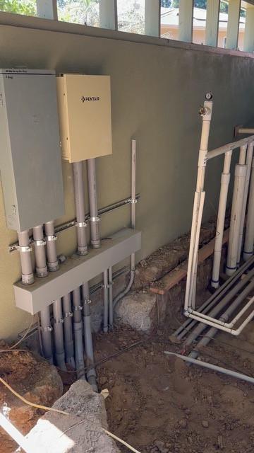 Plumbing manifold and conduit along an exterior wall beside a control box