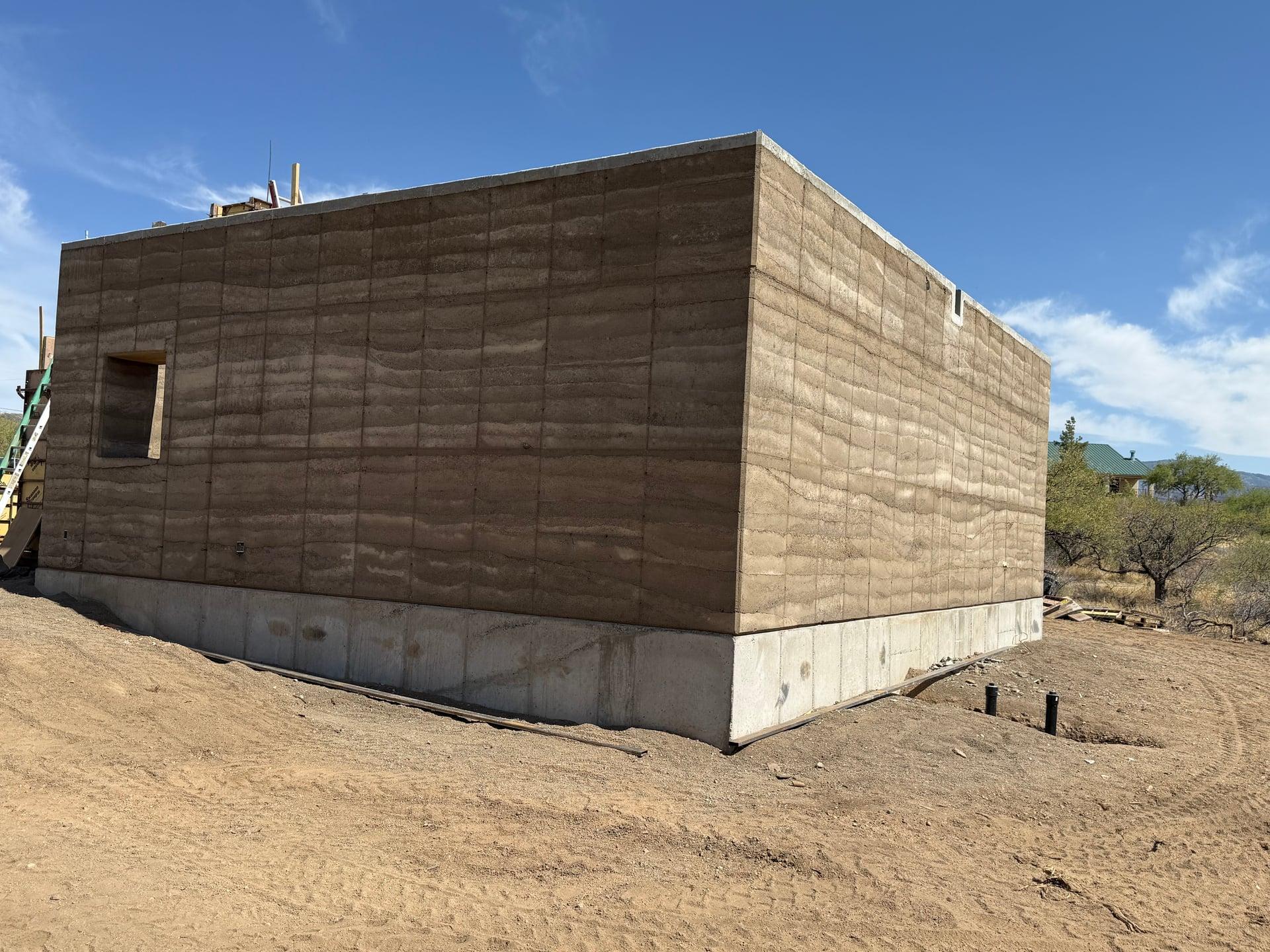 Freshly stripped monolithic rammed-earth corner walls on concrete stem wall
