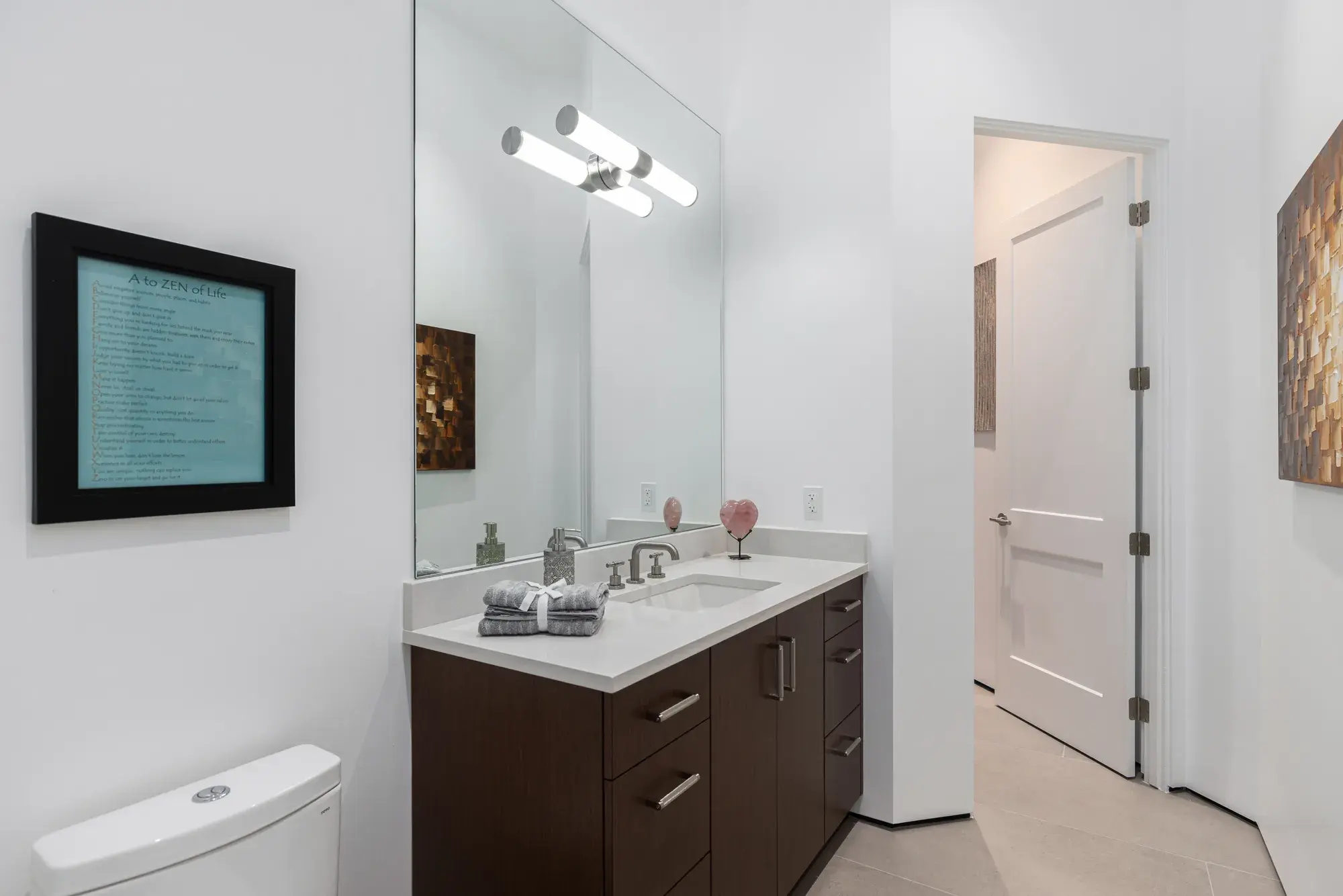 Bathroom with dark wood vanity, white quartz counter, and framed art