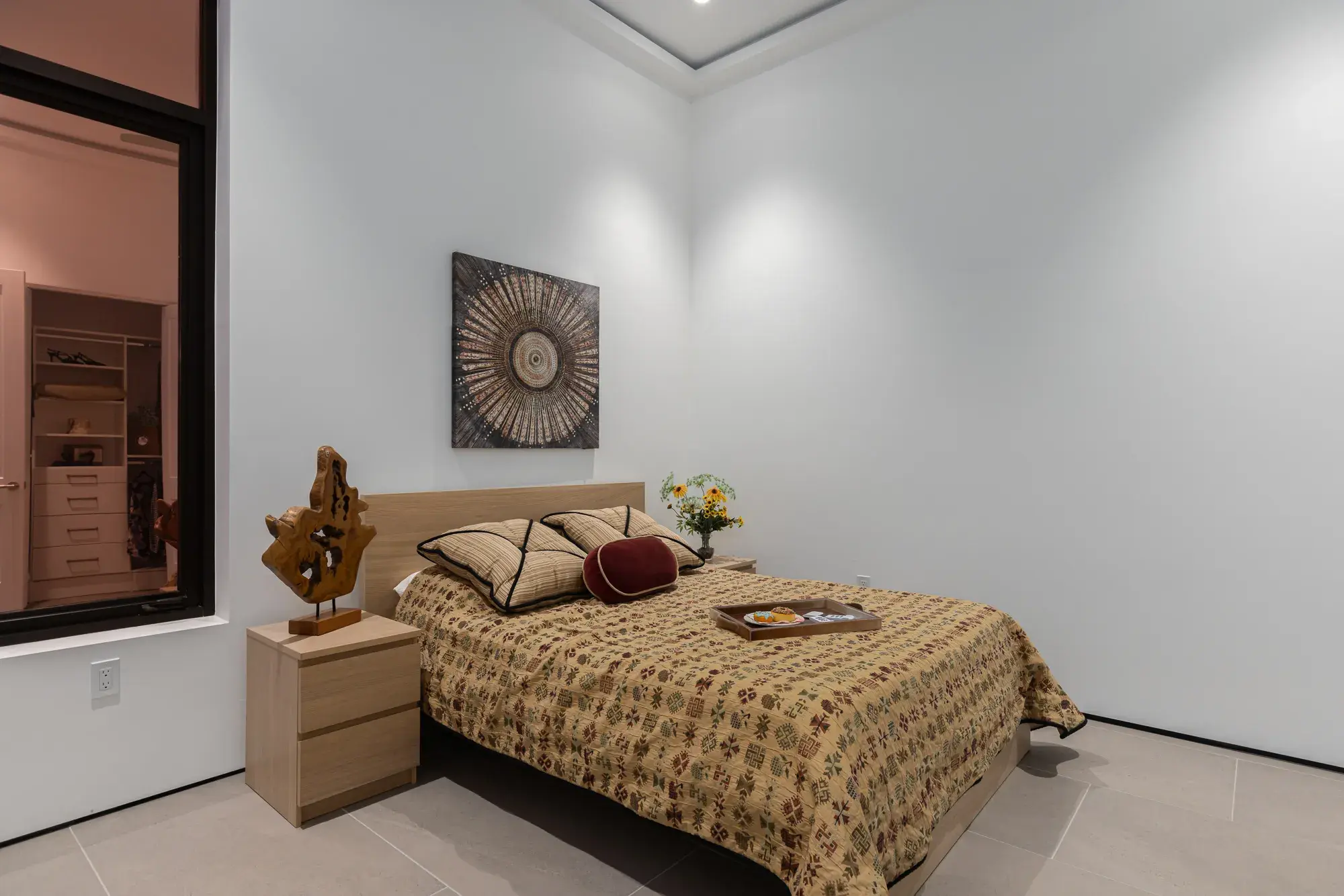 Bedroom with cove-lit ceiling and a window into the walk-in closet