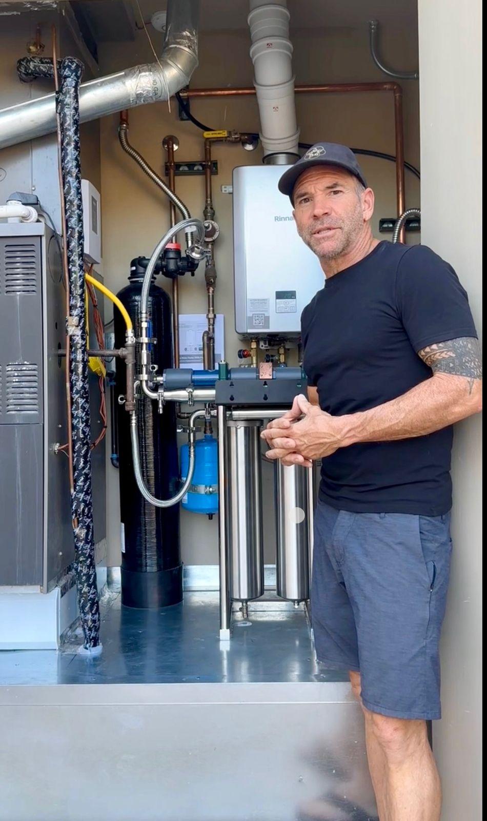 Brian Johnson beside the whole-home water system and tankless water heater in the mechanical room