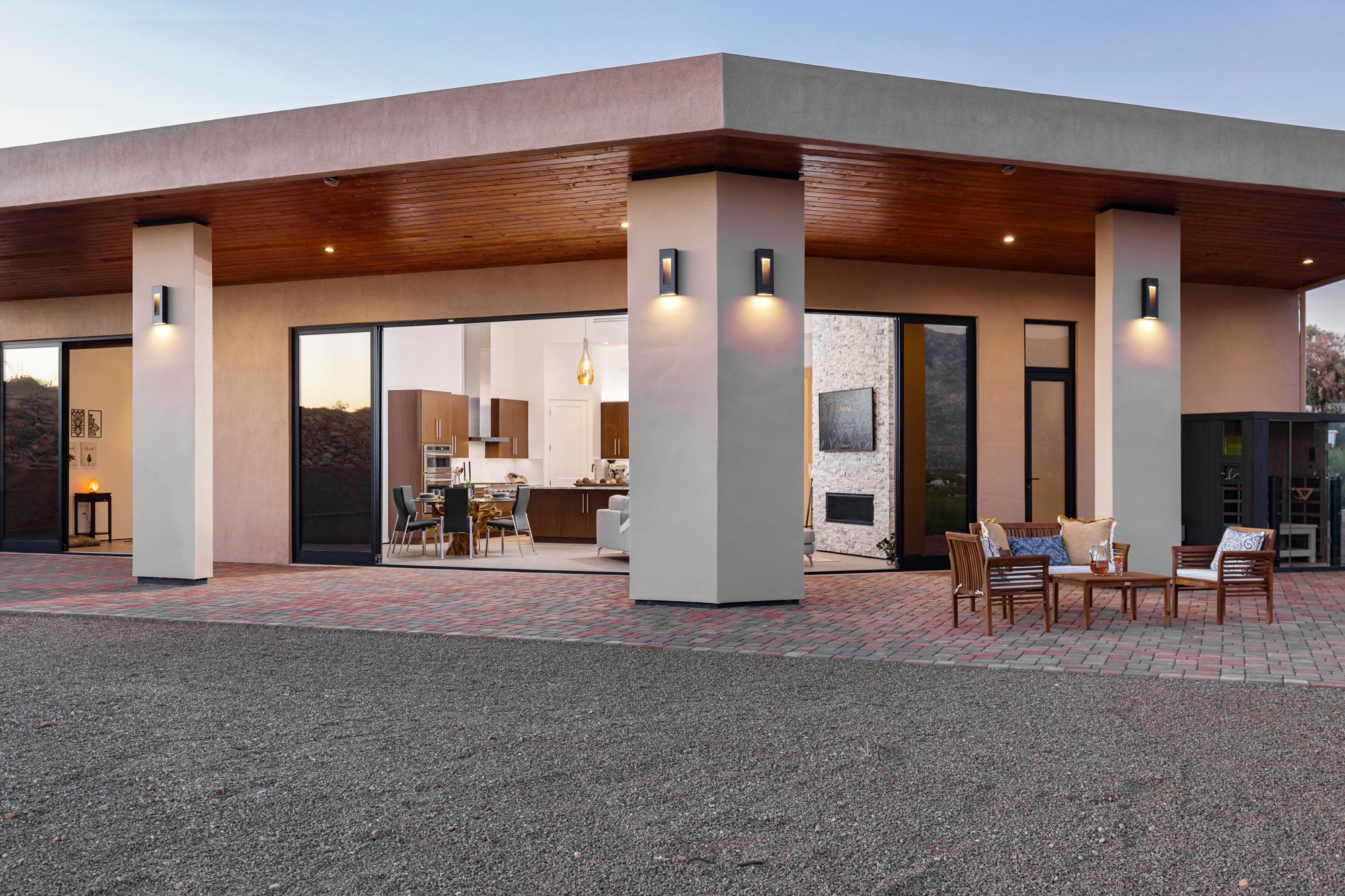 Covered patio at dusk with wall-height glass opening to the kitchen and great room