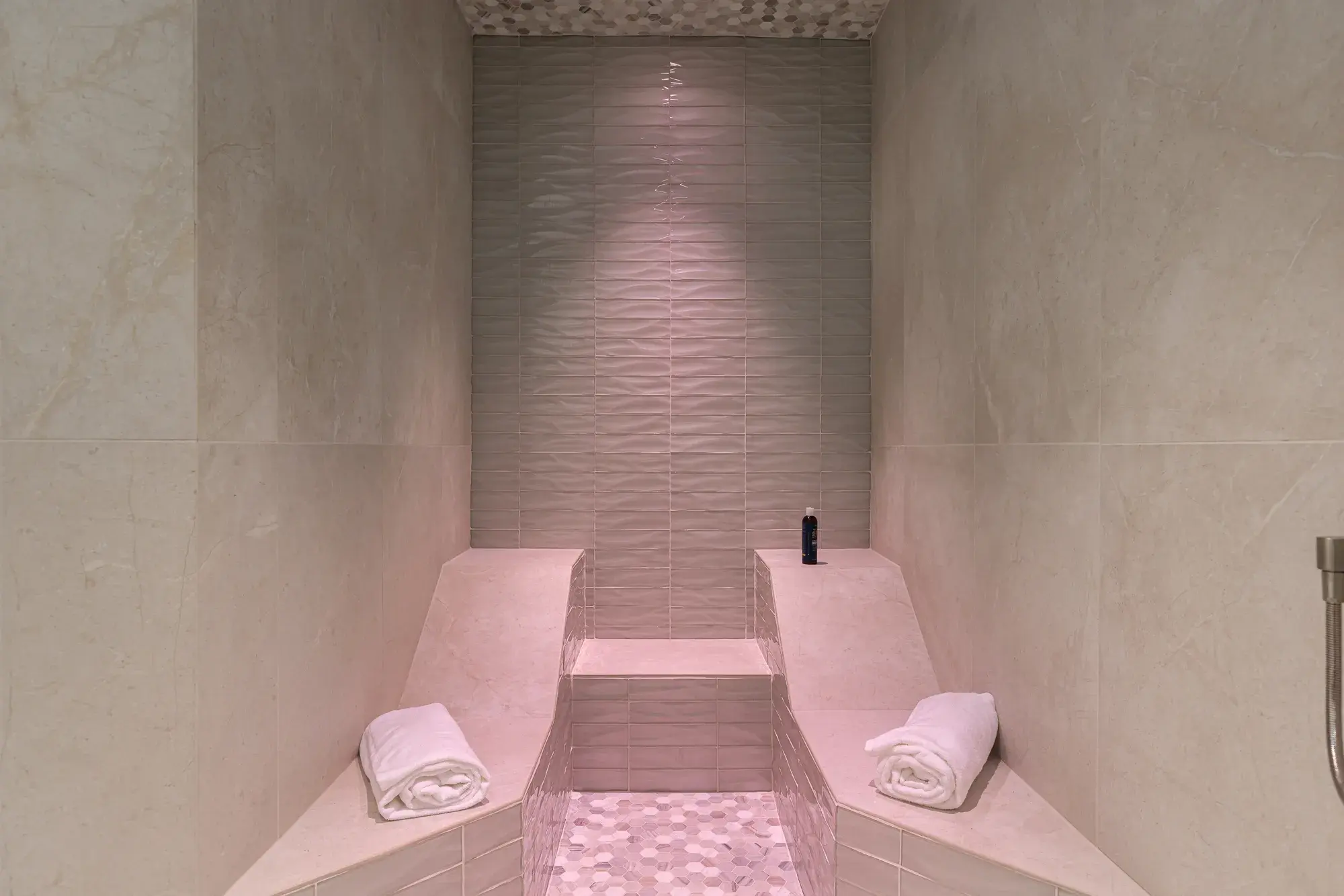 Tiled steam room with contoured benches and rolled towels