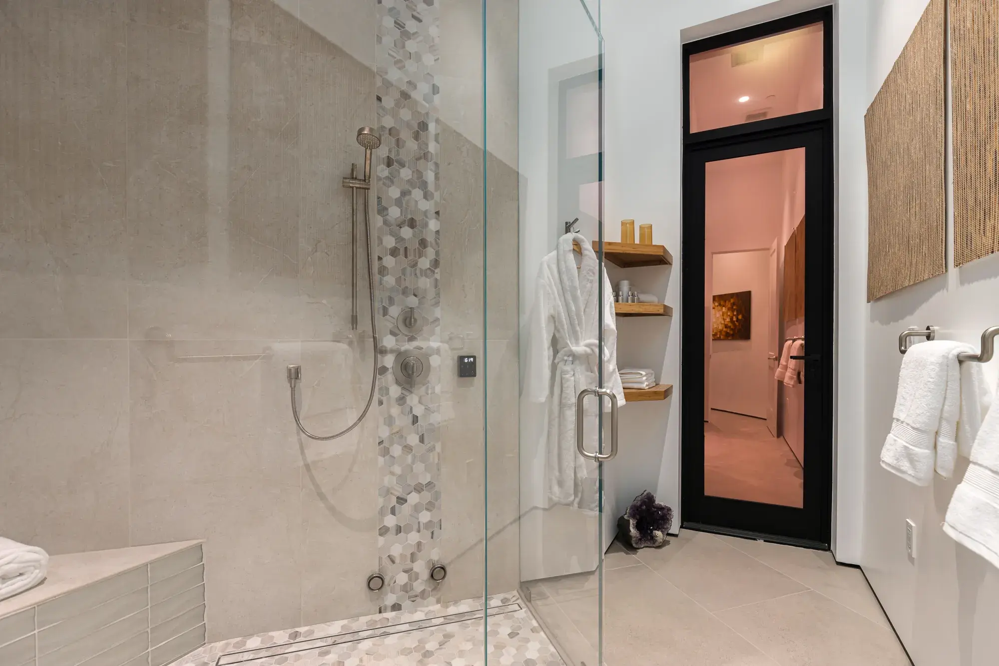 Walk-in glass shower with bench, hand shower, and mosaic tile accent