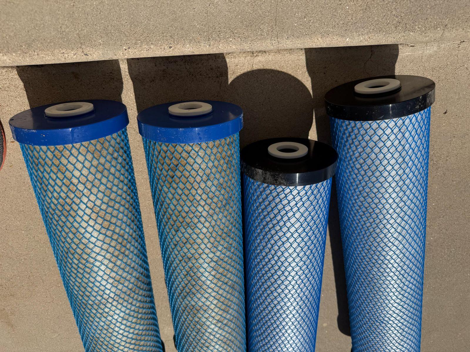 Four carbon block filter cartridges in blue mesh wraps