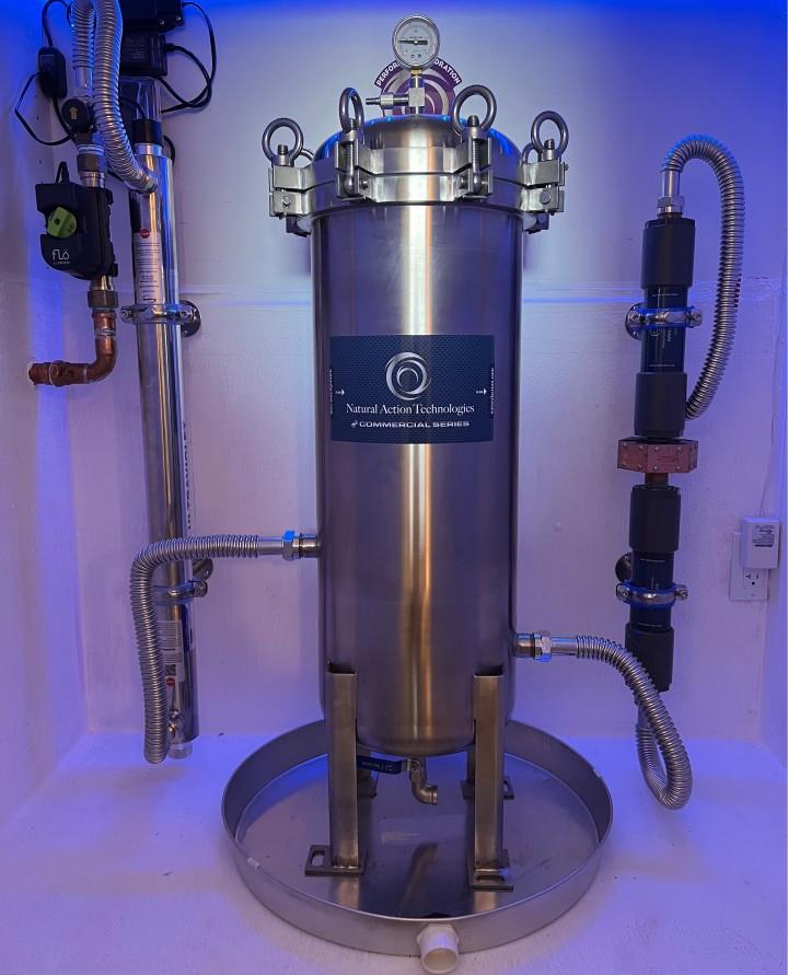 Stainless whole-home filter vessel with gauges, under blue accent lighting