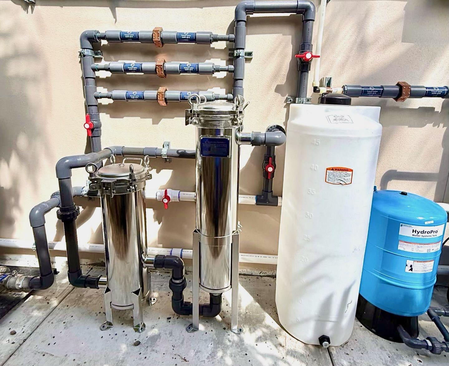 Stainless filter vessels with gray piping and storage tanks installed outdoors