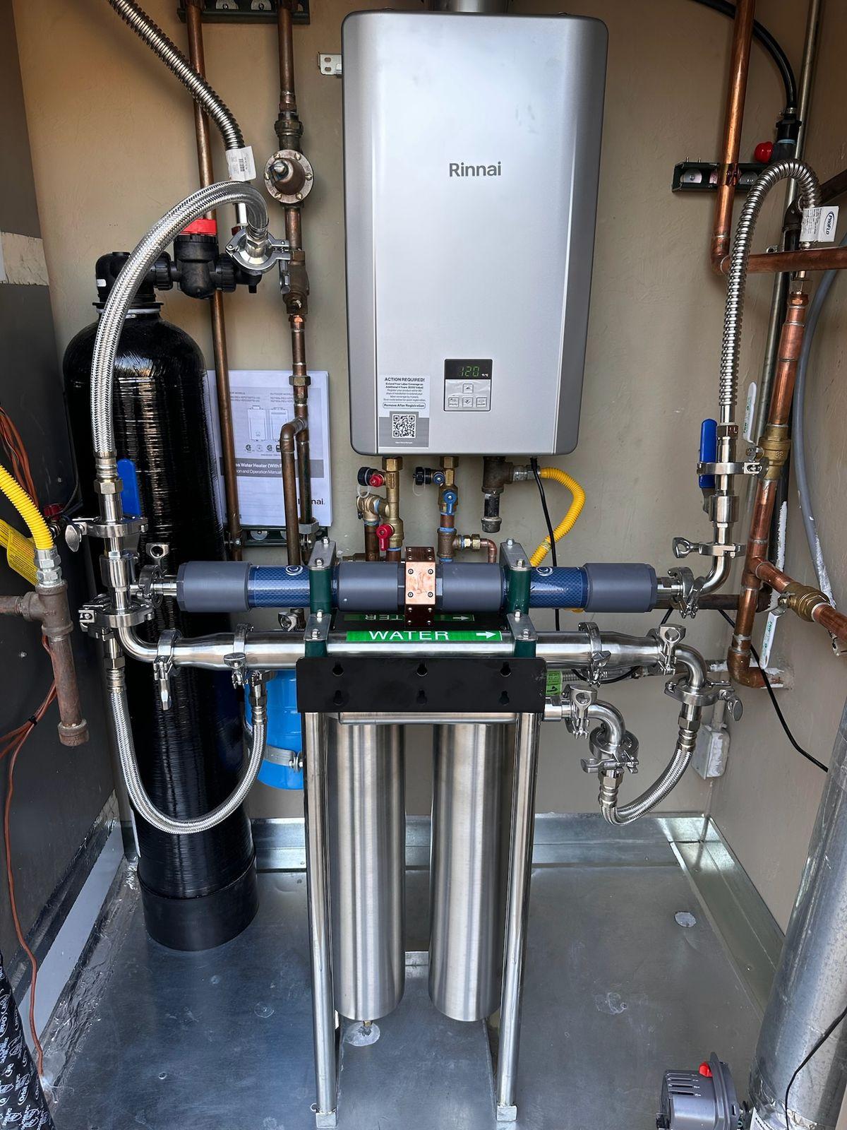 Whole-home structured water system installed beside a tankless water heater in a utility closet