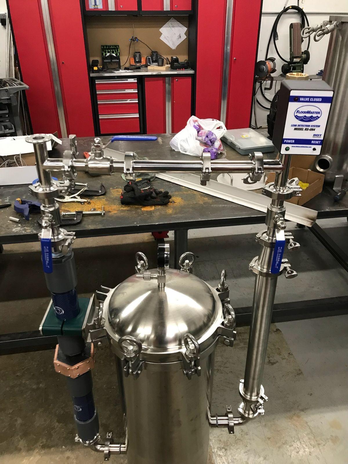 Stainless filter vessel and piping on a workbench in the fabrication shop