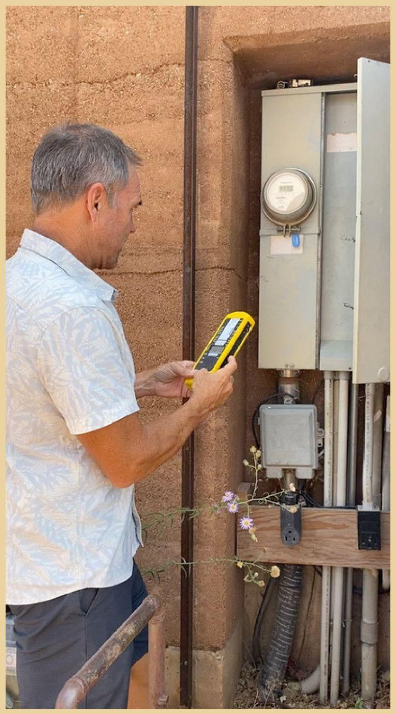 Brian Johnson taking a reading at an electrical panel with a handheld meter