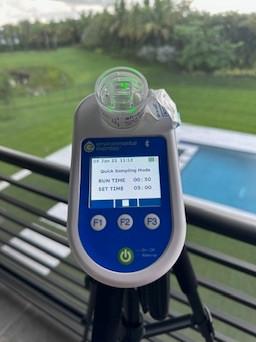 Environmental Express air sampling pump with a spore trap cassette on a tripod, on a balcony above the pool