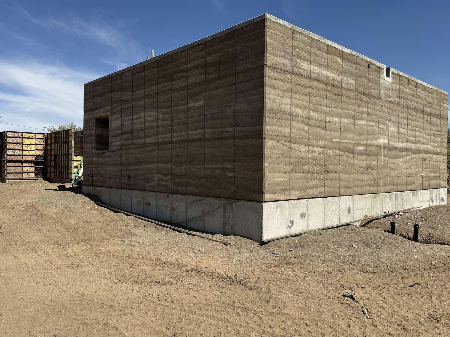 Clean cured rammed-earth corner meeting at the building edge