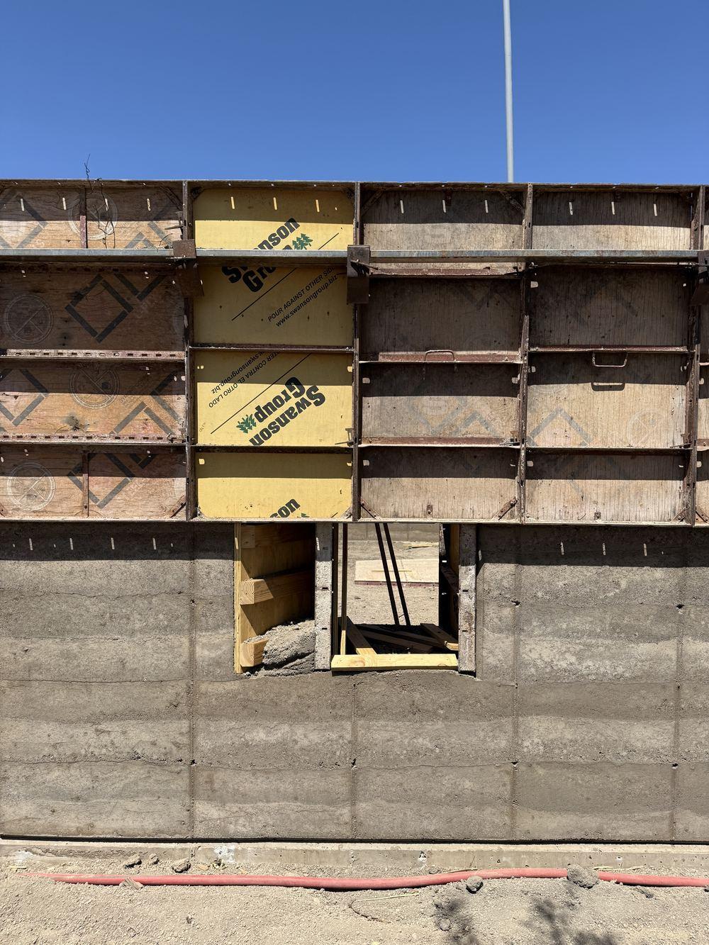 Formwork panels stacked around a window buck partway up a wall