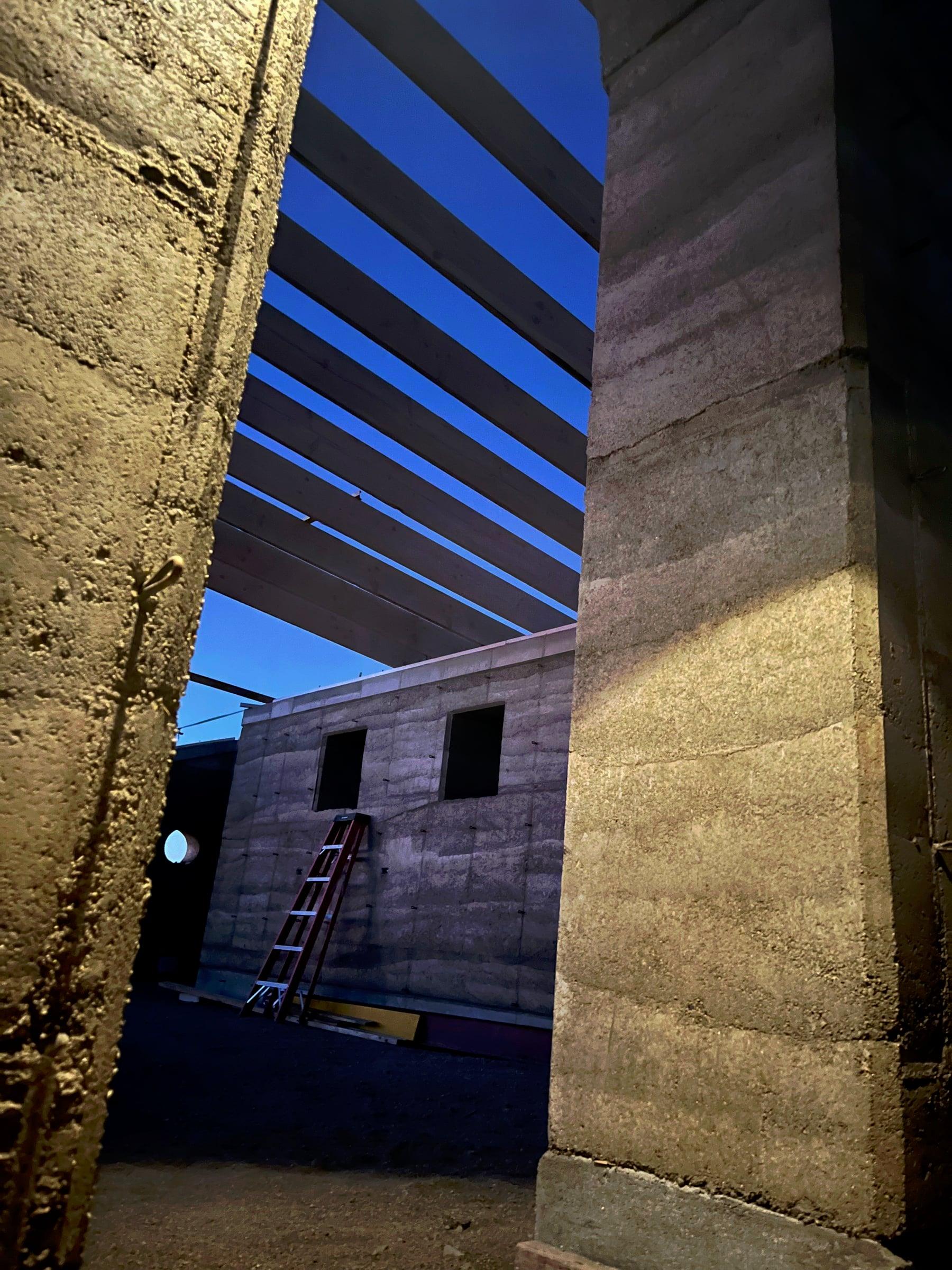 Wood roof beams spanning between rammed-earth columns