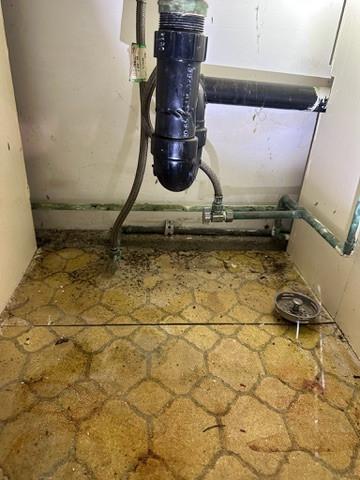 Stained, deteriorated cabinet floor beneath sink plumbing