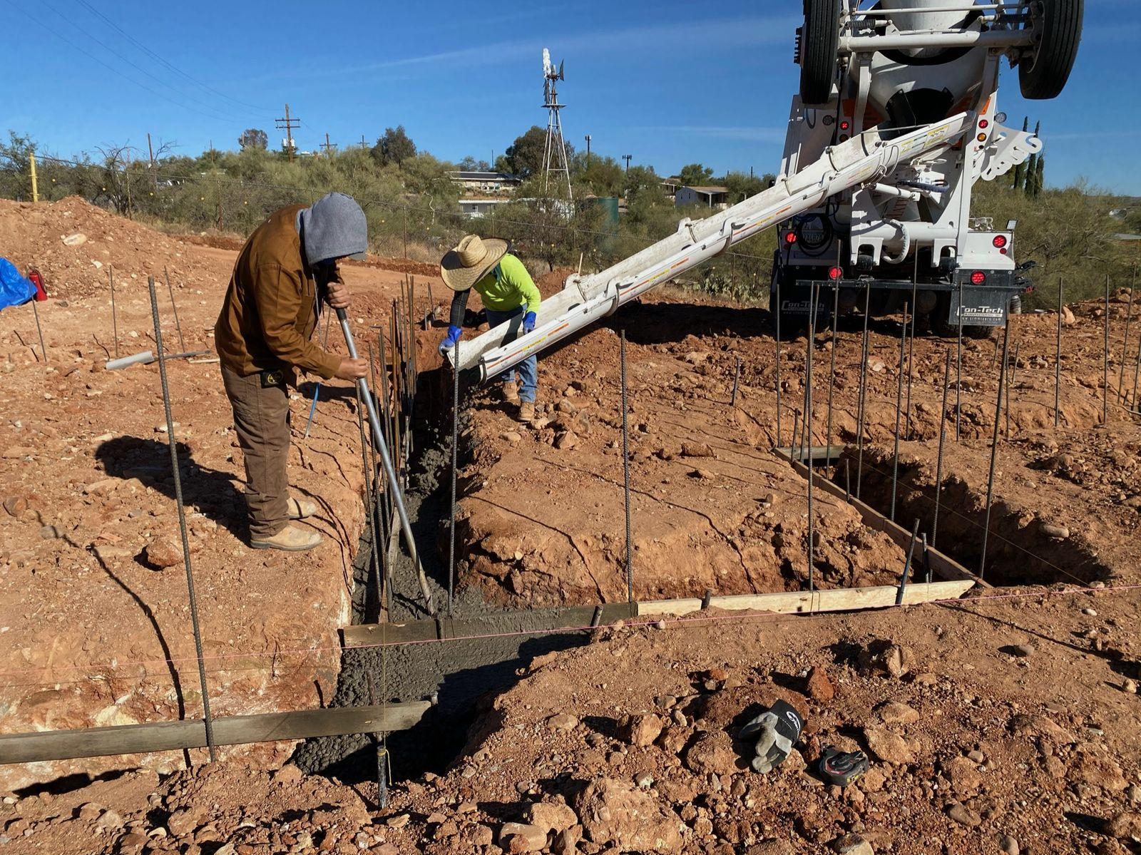 Crew pouring concrete into the footings
