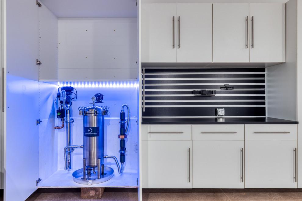 Blue-lit utility cabinet holding the stainless structured water filtration system beside white cabinetry