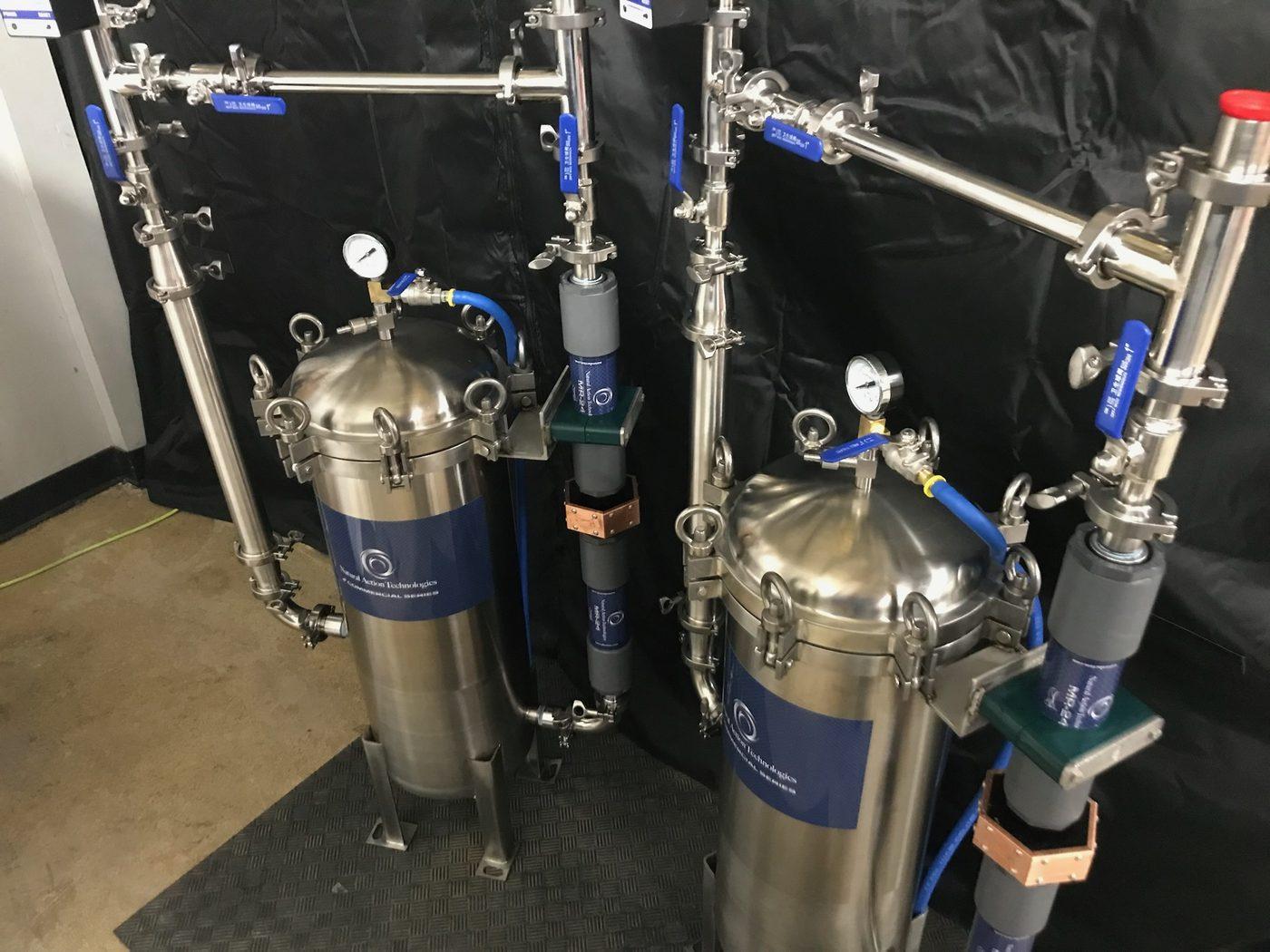 Stainless filtration skids under construction in the shop with tri-clamp piping, gauges, and inline structured-water units