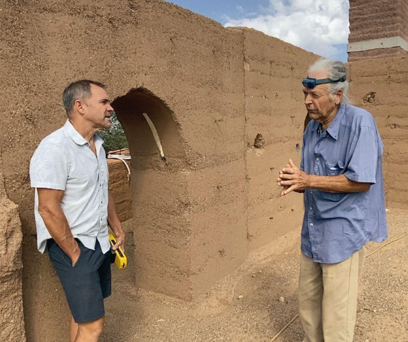 Brian Johnson talking with a mentor beside a rammed earth wall