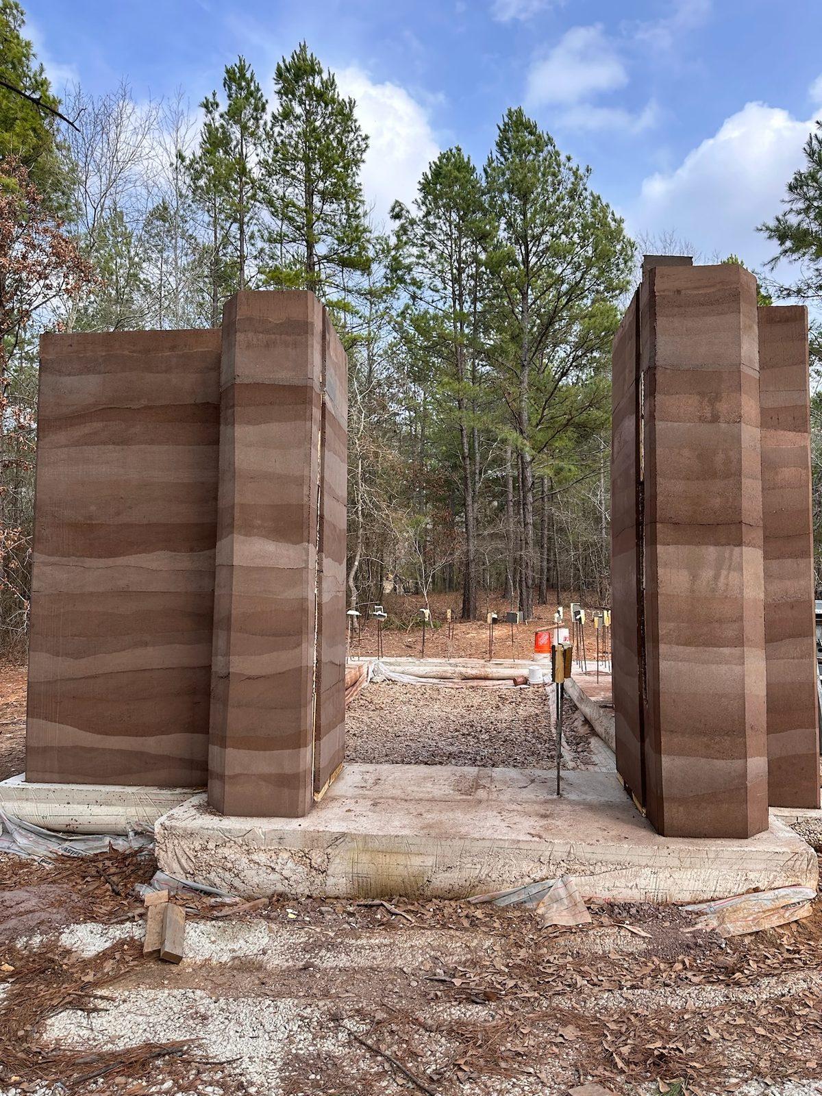 Rammed earth panels standing among pine trees