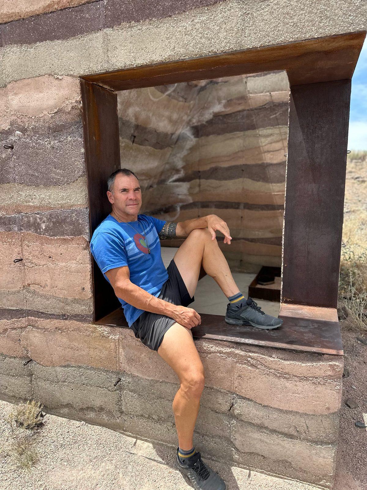 Brian Johnson sitting in a window opening of a rammed earth wall